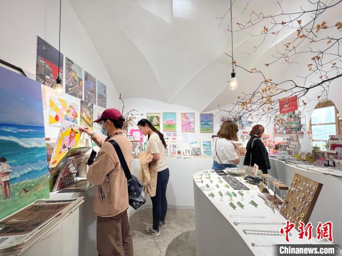 圖為藝術(shù)品商店內(nèi)，顧客挑選插畫(huà)作品?！＄婌?攝