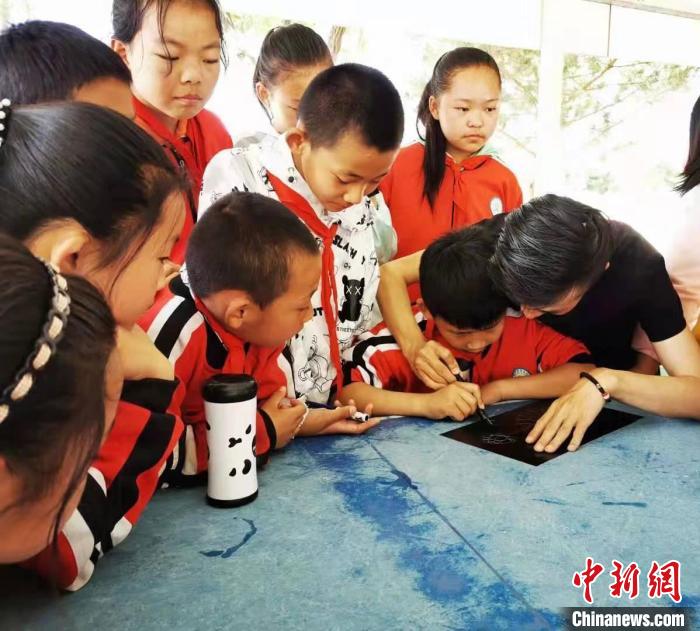 圖為朱增平(右一)教學生創(chuàng)作鍥金畫。(資料圖) 受訪者供圖