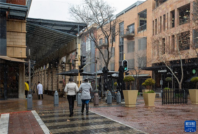 7月10日，在南非約翰內(nèi)斯堡一處商業(yè)區(qū)，人們在雪中行走。新華社記者 張譽(yù)東 攝