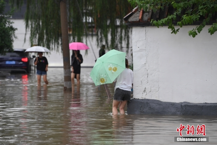 7月31日，市民行走在雨中的北京房山區(qū)瓦窯頭村。北京市氣象臺(tái)當(dāng)日10時(shí)發(fā)布分區(qū)域暴雨紅色預(yù)警信號(hào)。北京市水文總站發(fā)布洪水紅色預(yù)警，預(yù)計(jì)當(dāng)日12時(shí)至14時(shí)，房山區(qū)大石河流域?qū)⒊霈F(xiàn)紅色預(yù)警標(biāo)準(zhǔn)洪水。<a target='_blank' href='/'><p  align=