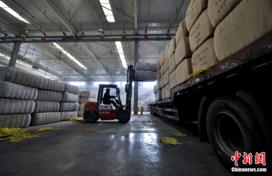 新疆喀什綜合保稅區(qū)，喀什啟路國際貿(mào)易有限公司的倉庫內(nèi)，工人正在裝載從塔吉克斯坦和烏茲別克斯坦進口的棉花。劉新攝