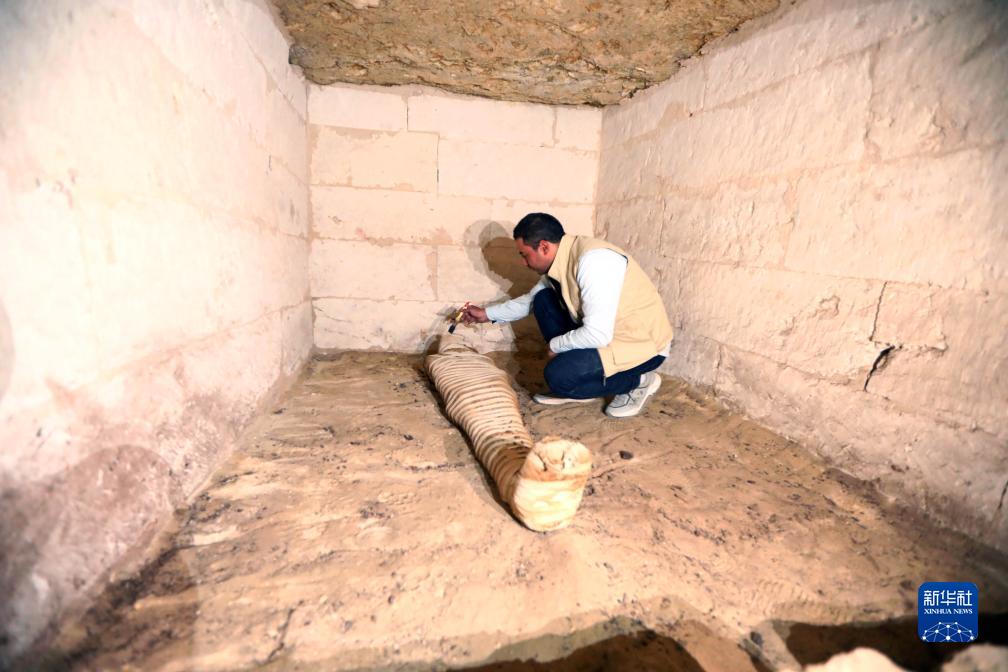 10月15日，在埃及明亞省考古現(xiàn)場(chǎng)，考古人員清理一座石鑿墓中的木乃伊。新華社發(fā)（艾哈邁德·戈馬攝）