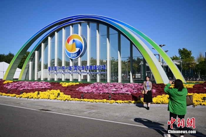 10月15日，北京，工作人員在國家會議中心外的第三屆“一帶一路”國際合作高峰論壇景觀布置前拍照留念。當(dāng)日，位于國家會議中心的第三屆“一帶一路”國際合作高峰論壇新聞中心啟動試運行。據(jù)悉，第三屆“一帶一路”國際合作高峰論壇將于10月17日至18日在北京舉行。<a target='_blank' href='/'><p  align=