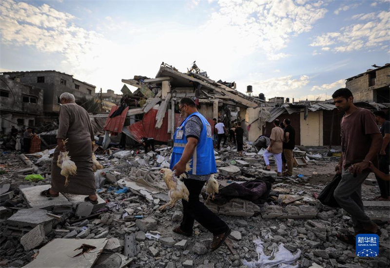 10月27日，在加沙地帶南部城市汗尤尼斯，人們經(jīng)過以軍襲擊后的房屋廢墟。
