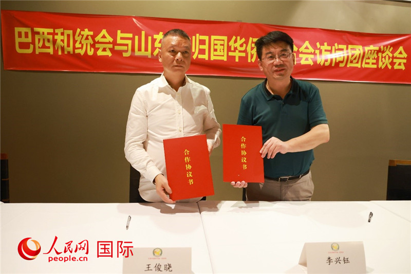 中國僑聯(lián)副主席、山東省僑聯(lián)主席李興鈺（右）與巴西和統(tǒng)會會長王俊曉簽署合作協(xié)議書。人民網(wǎng)記者 陳海琪攝