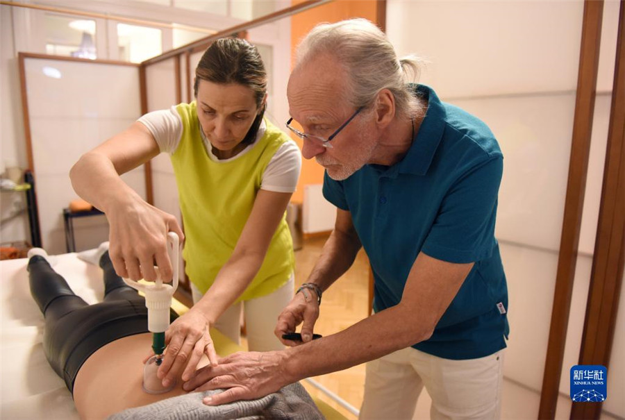 12月12日，在奧地利維也納，科格勒醫(yī)生（右）和助手在為病人進行拔罐治療。新華社記者 賀燦鈴 攝