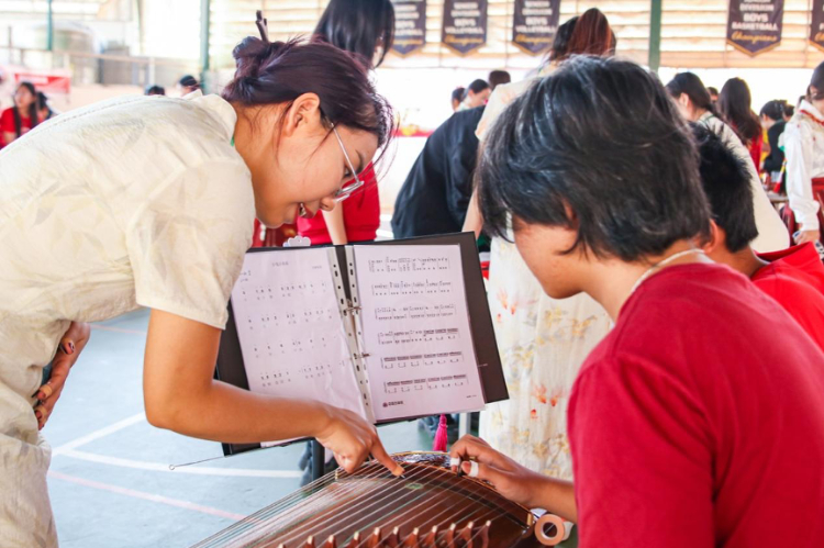 志愿者教師指導(dǎo)學(xué)生彈奏古箏?；顒又鬓k方供圖