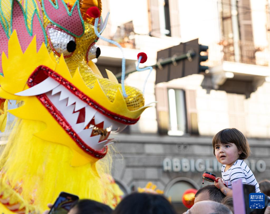 2月18日，在意大利羅馬，一名小朋友在彩妝巡游上觀看舞龍。新華社記者 李京 攝