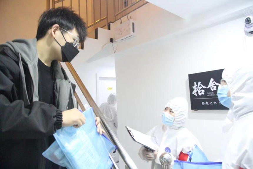 社區(qū)工作人員和志愿者身穿防護(hù)服上門(mén)送馬應(yīng)龍大健康防疫包。徐帥攝