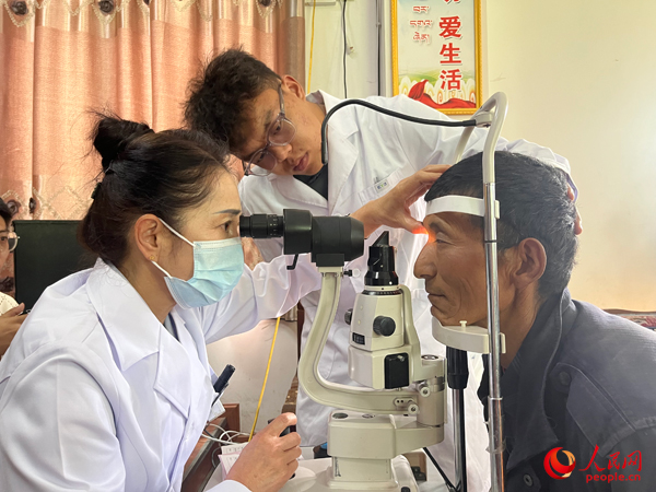王紅英（左）和團(tuán)隊(duì)成員為達(dá)熱村村民檢查眼睛。人民網(wǎng)記者 杜燕飛攝