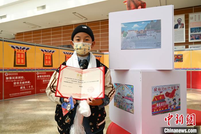 圖為一名獲獎(jiǎng)學(xué)生與自己的繪畫作品合影?！≮w朗 攝