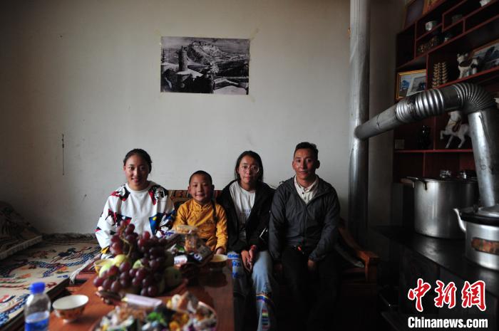 圖為8月12日，2018年7月從距那曲市色尼區(qū)城區(qū)那曲鎮(zhèn)90千米外的古露鎮(zhèn)當(dāng)桑村搬遷至城區(qū)的旦增(右一)與家人在80多平方米的新家合影(資料圖)。　張偉 攝