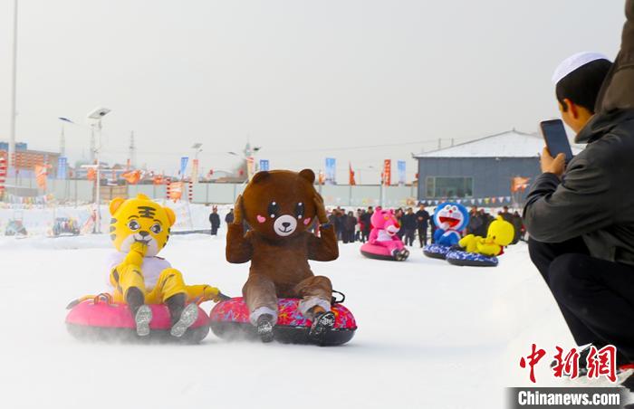 圖為臨夏市南龍鎮(zhèn)馬家莊村舉辦的鄉(xiāng)村文化旅游節(jié)上，游客穿著卡通服裝在體驗雪上飛碟項目。近年來，臨夏州形成了“春賞花、夏避暑、秋摘果、冬玩雪”的全季節(jié)旅游產(chǎn)品體系。(資料圖) 高展 攝