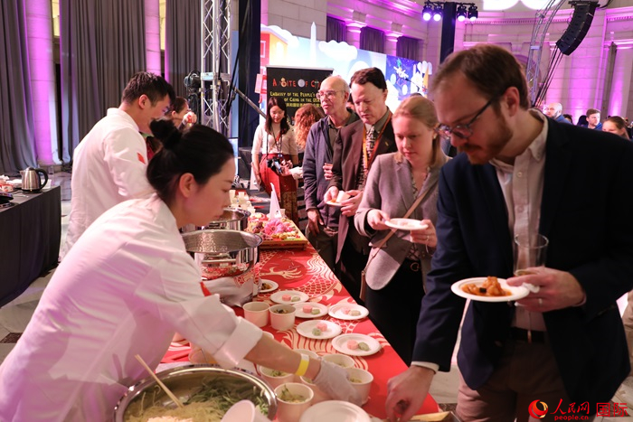 當?shù)貢r間3月7日晚，華盛頓聯(lián)合車站廣場舉行駐美使團“使館主廚挑戰(zhàn)賽”。圖為當?shù)孛癖娫谥袊古_前體驗中國美食。人民網(wǎng)記者 李志偉攝
