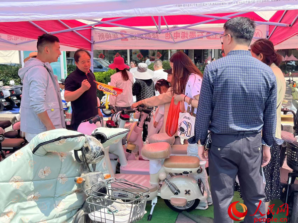 某電動(dòng)自行車(chē)品牌工作人員向消費(fèi)者介紹以舊換新相關(guān)情況。人民網(wǎng)記者 杜燕飛攝