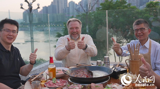 康寧顯示科技事業(yè)部全球拓建項(xiàng)目總監(jiān)軻寶華（中）和同事在重慶南濱路吃火鍋。人民網(wǎng)記者 蘇纓翔攝