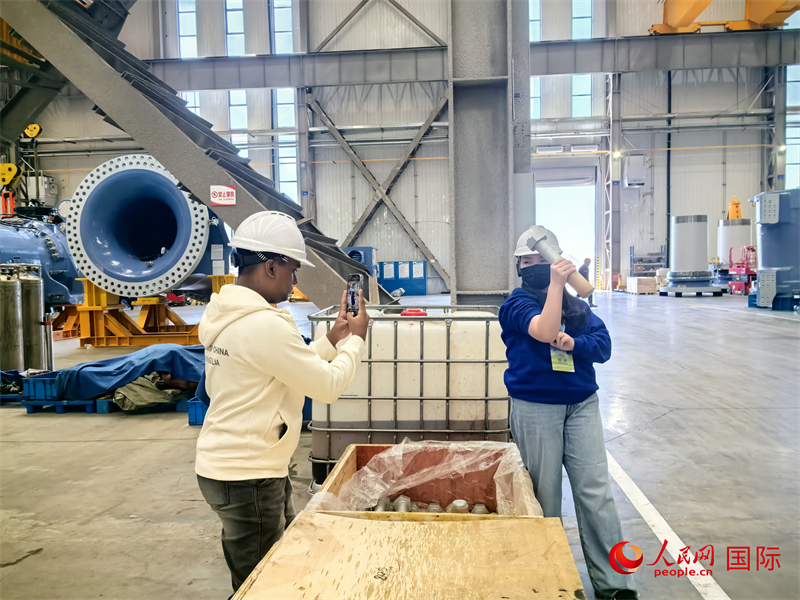 外媒記者掂量廠房?jī)?nèi)的巨型螺栓。人民網(wǎng) 楊春燕攝