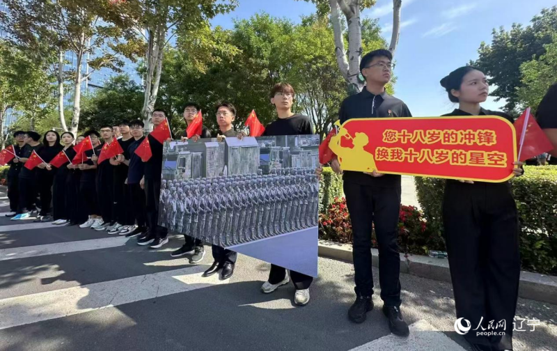 沈陽市人民廣場上，大學(xué)生們手持閱兵的圖片，告慰英烈。人民網(wǎng)記者 周頌雪攝