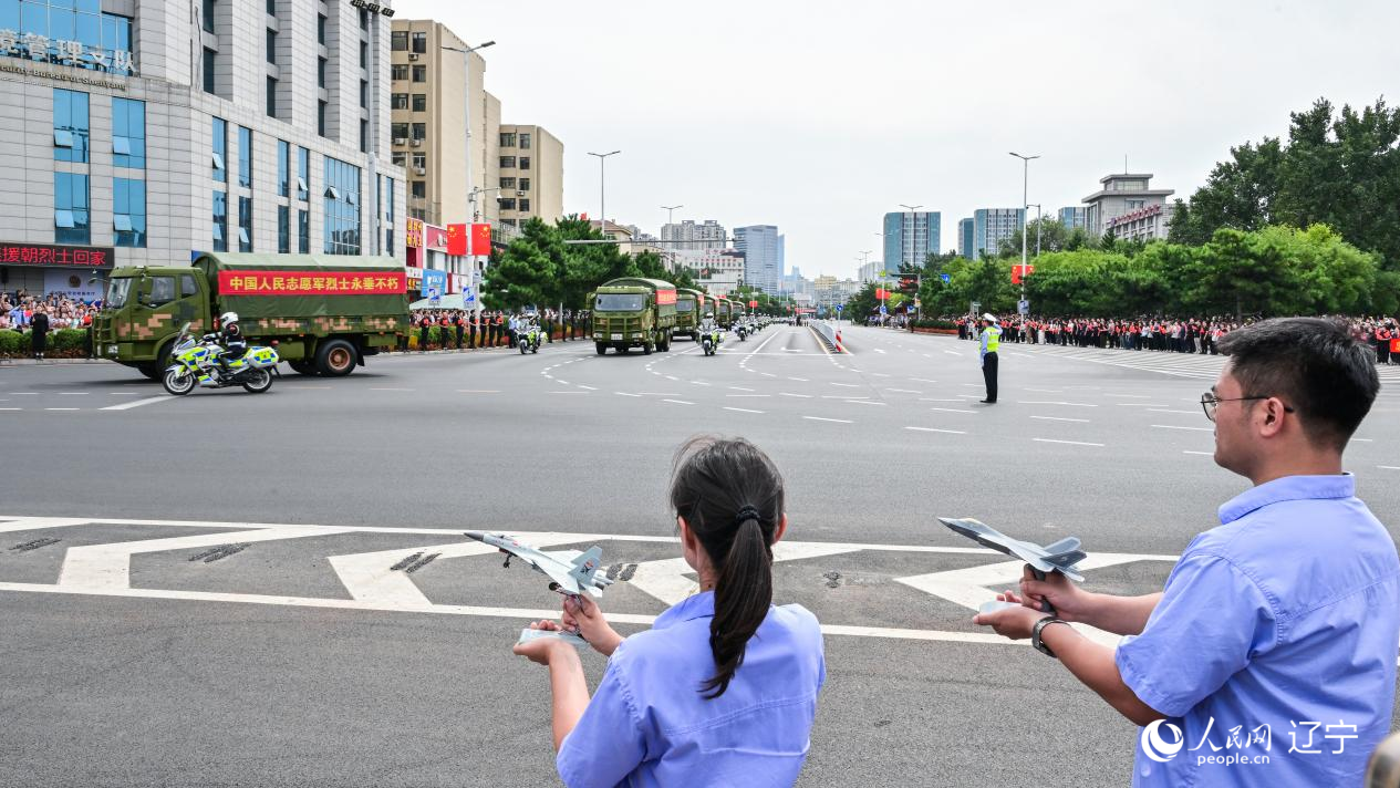 航空工業(yè)沈飛的青年技術(shù)人員拿著受閱戰(zhàn)機(jī)的模型迎接烈士遺骸。航空工業(yè)沈飛供圖