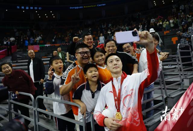 11月12日，十五運(yùn)會男籃成年組決賽，廣東隊(duì)獲得冠軍后，胡明軒與球迷們合影留念。張由瓊 攝