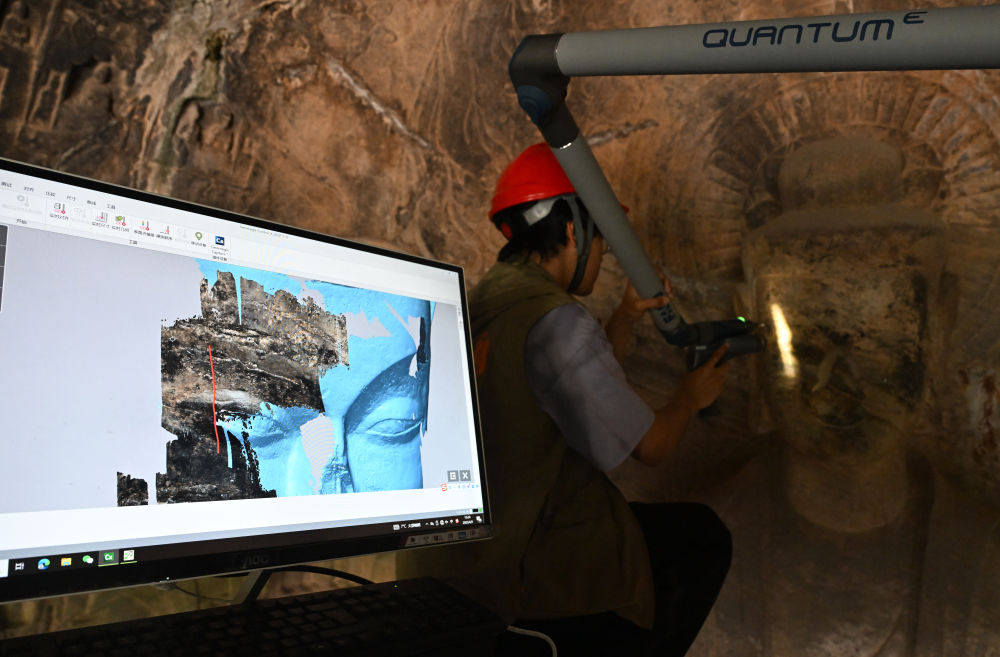 2025年4月9日，武漢大學(xué)文化遺產(chǎn)智能計(jì)算實(shí)驗(yàn)室團(tuán)隊(duì)成員在魏字洞使用關(guān)節(jié)臂掃描儀對(duì)佛像進(jìn)行數(shù)字化掃描。圖片來源新華社