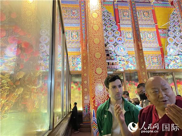 7月25日，省級非物質(zhì)文化遺產(chǎn)項目塔爾寺酥油花的代表性傳承人朋措堅參（右）在塔爾寺酥油花館講解酥油花的制作過程。人民網(wǎng) 謝瑩攝