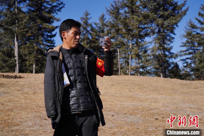 圖為桑杰加進行巡查并拍照記錄?！●R銘言 攝