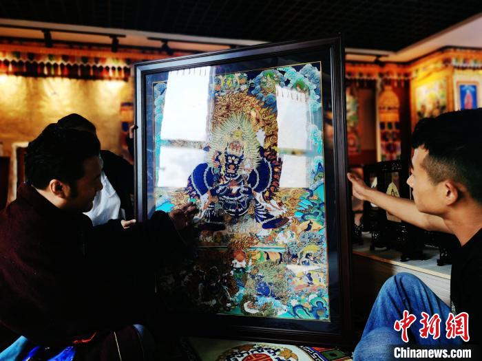 圖為久美尖措(左)與徒弟們展示唐卡作品?！?zhí)砀?攝