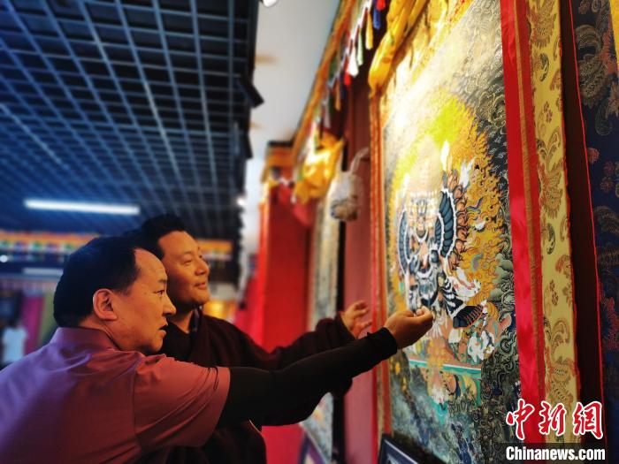 圖為久美尖措展示唐卡作品?！?zhí)砀?攝