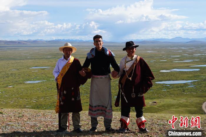 圖為一名留學(xué)生身穿自己國家的服飾和藏族民眾合影留念?！●R銘言 攝