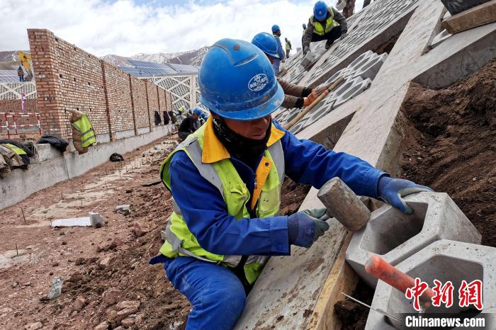 圖為光伏發(fā)電項(xiàng)目施工區(qū)工人在護(hù)坡鋪設(shè)空心磚?！±铍h 攝