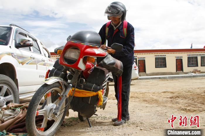 圖為白瑪準(zhǔn)備騎摩托車巡湖?！≮w朗 攝