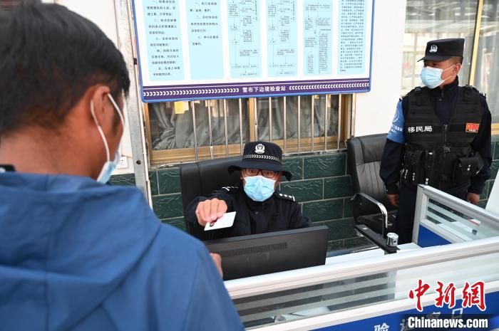 圖為移民管理警察登記完身份信息后將證件歸還給行人?！≮w朗 攝