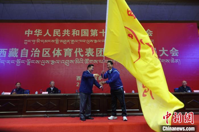 西藏自治區(qū)副主席甲熱·洛桑丹增授代表團(tuán)團(tuán)旗，西藏自治區(qū)體育局局長(zhǎng)尼瑪次仁接旗。　冉文娟 攝