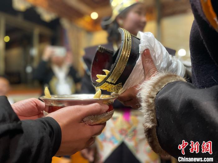 圖為主人在碗中斟滿青稞酒?！∪轿木?攝