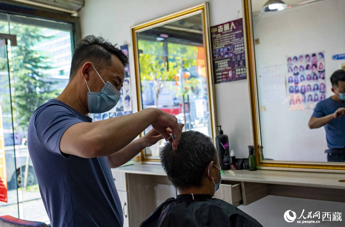 理發(fā)店老板為顧客理發(fā)。次仁羅布 攝