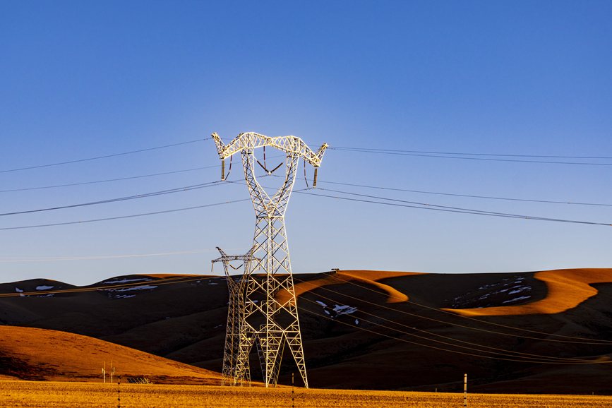 阿里地區(qū)的曠野上，電力鐵塔在夕陽下熠熠生輝。