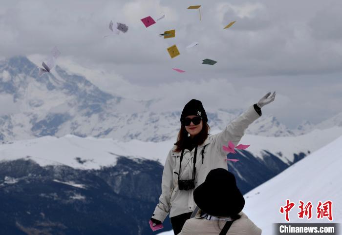 圖為5月14日，游客在西藏林芝色季拉山觀景臺(tái)拋灑“隆達(dá)”(風(fēng)馬旗，藏族民眾的一種祈福方式)?！±盍?攝