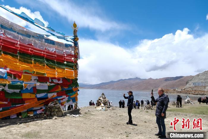 進(jìn)藏參訪(fǎng)嘉賓在羊湖畔拍攝經(jīng)幡?！〗w波 攝