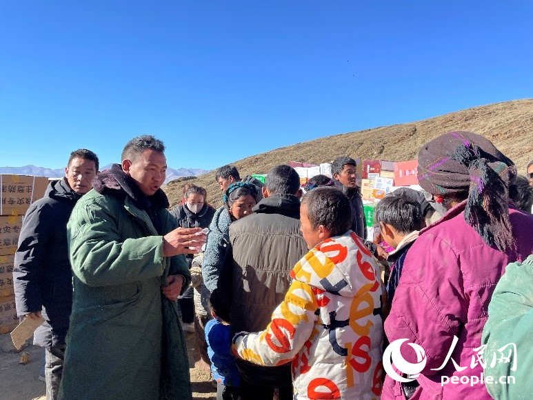 定日縣公安局干警頓珠次仁（左二）正在協(xié)助分發(fā)物資。人民網(wǎng)記者 郝潔攝