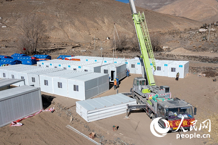 1月9日，在日喀則市定日縣長所鄉(xiāng)古榮村安置點，救援人員和施工人員合力抓緊搭建移動板房，確保受災群眾溫暖過冬。人民網記者 翁奇羽攝
